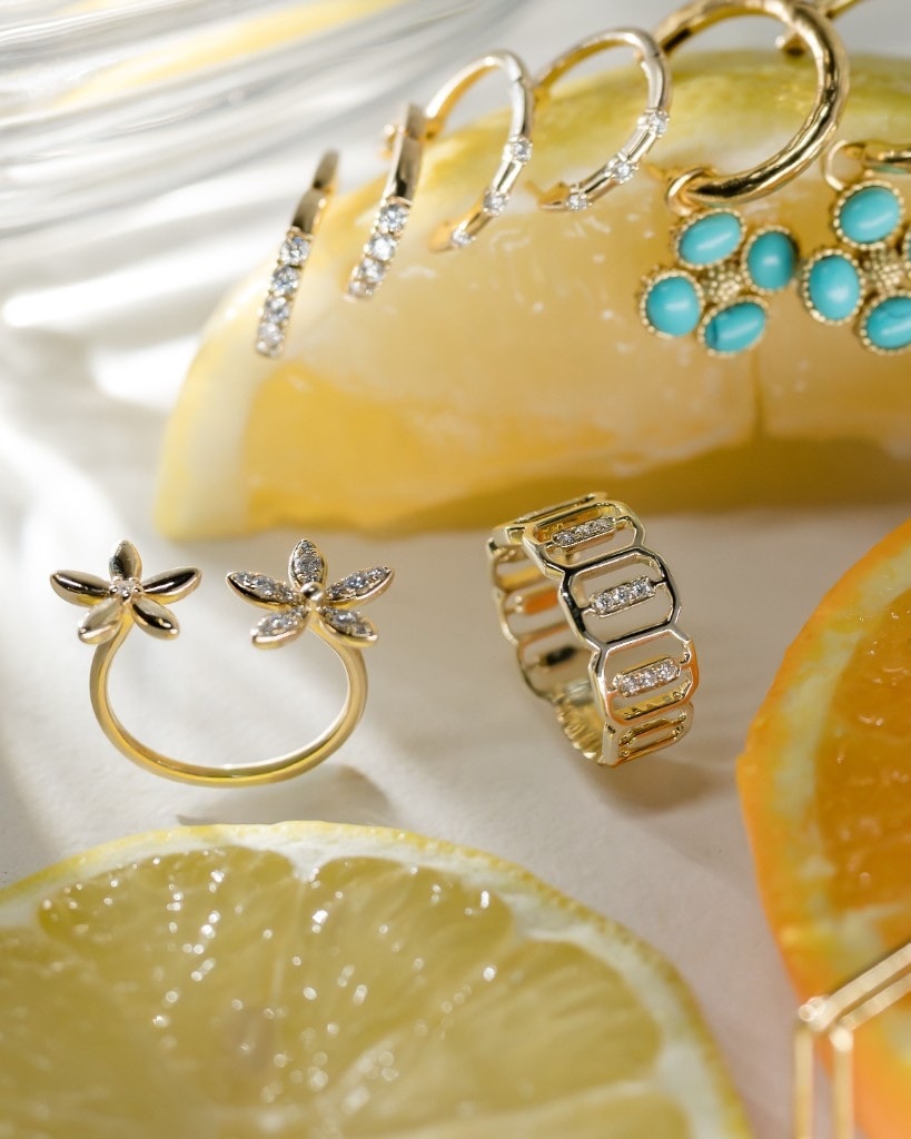 Gold and diamond earrings styled beside fresh citrus