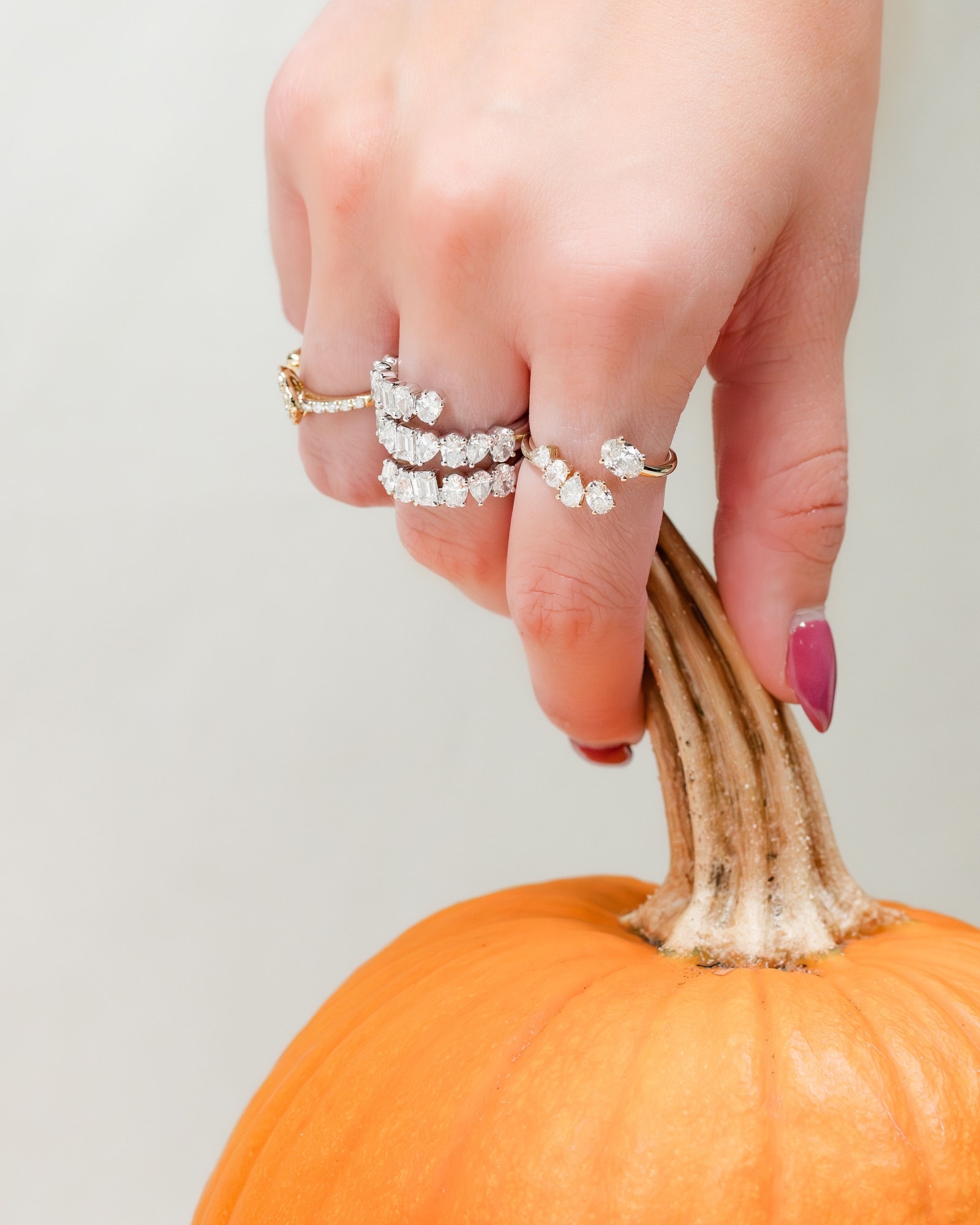 Diamond rings worn on a hand holding the stem of a fall pumpkin