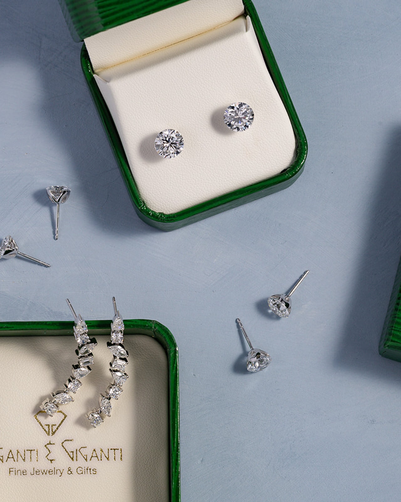 Diamond stud and climber earrings presented in green Giganti & Giganti jewelry boxes