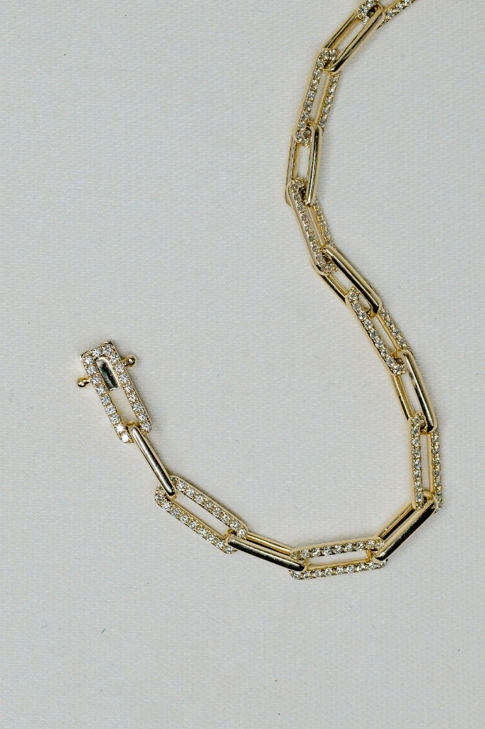 Diamond pavé paperclip-link bracelet in yellow gold on a cream background