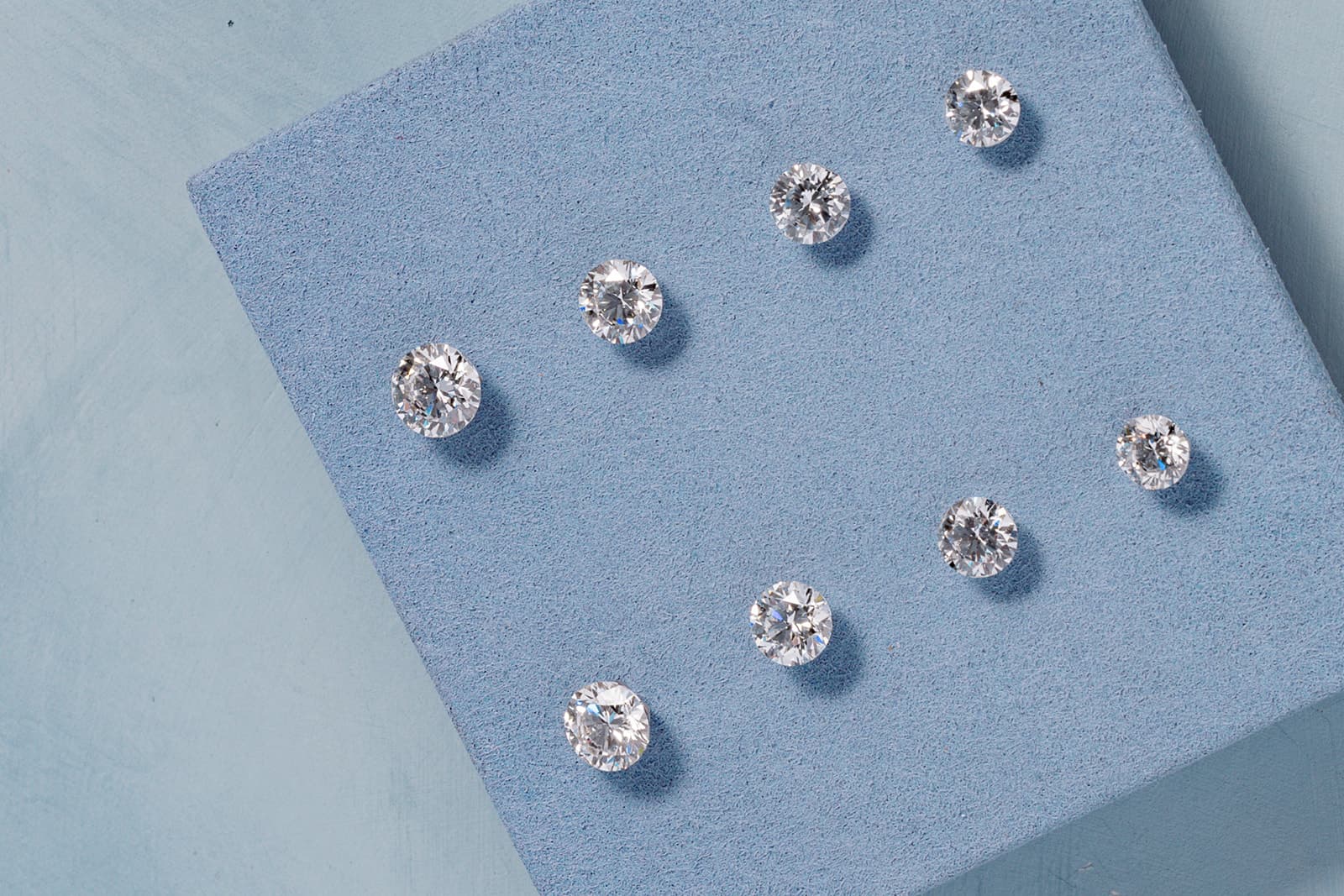 Loose round-brilliant diamonds arranged on a soft blue surface