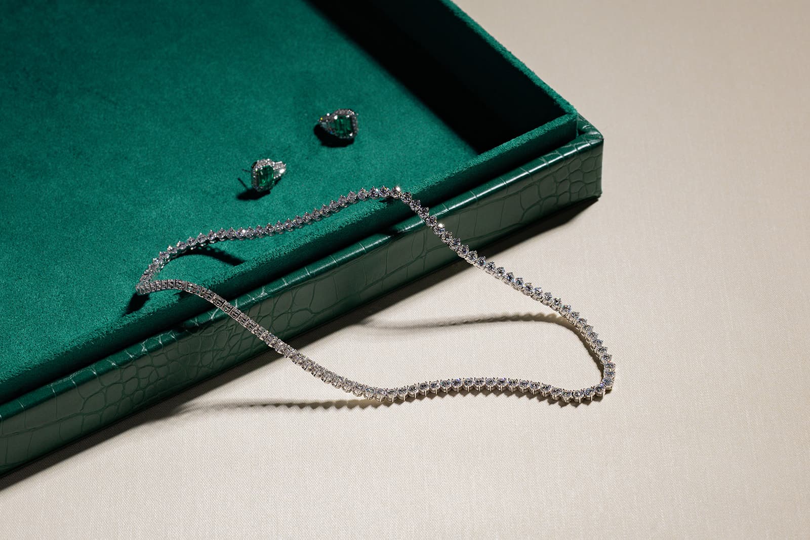 Diamond tennis necklace and earrings on emerald velvet jewelry box
