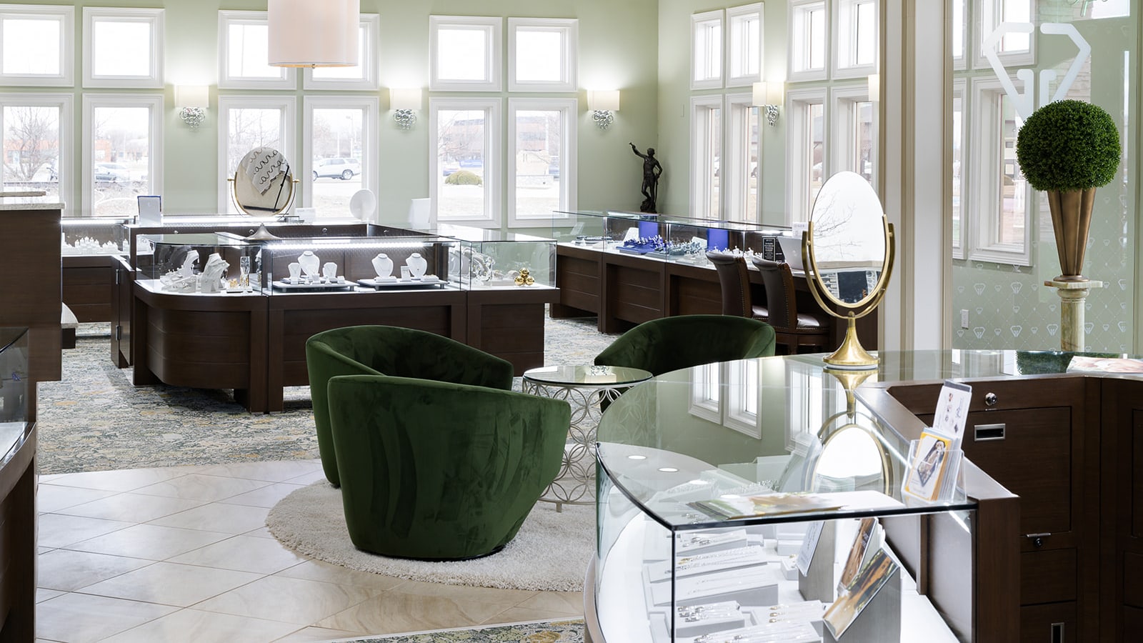 The Giganti & Giganti showroom at 3325 Robbins Road in Springfield, IL: sage walls, jewelry cases lining the windows, and the green velvet conversation chairs in the center