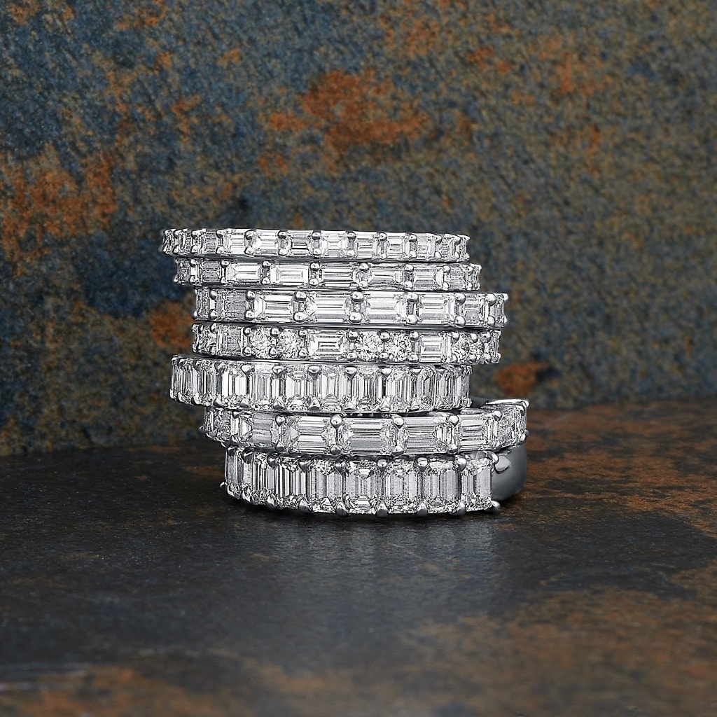 Tower of baguette and emerald-cut diamond eternity bands in white gold on dark stone